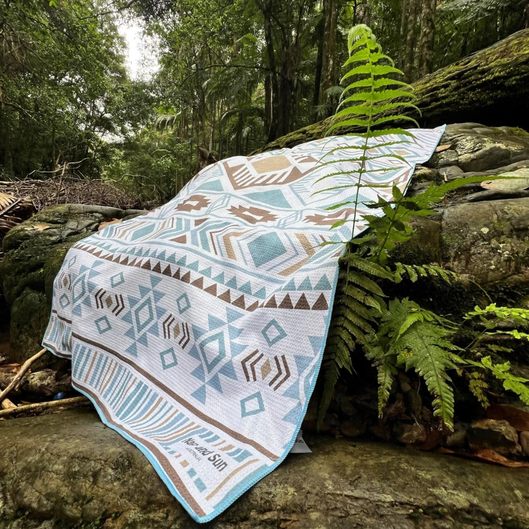 Our Azure towel laid out on a rock surrounded by lush greenery in a peaceful forest setting.