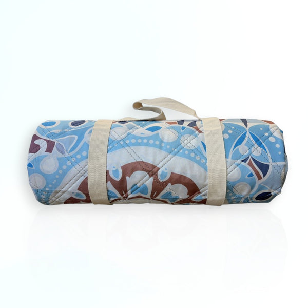 Nap and Sun Mandala Magic pattern picnic blanket rolled up with a beige carry strap securely attached around it.