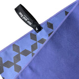 Close-up of Nap and Sun indigo blue gym towel showing the front and back. The front is a light blue with a black star pattern, while the back is a darker indigo blue. A black hook with a press stud is attached for easy hanging.