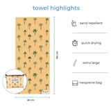 Full-size Nap and Sun Sunset Palms yellow towel with palm tree patterns displayed with matching neoprene wetbag. Text overlay highlights features: sand repellent, quick drying, extra large, neoprene bag.