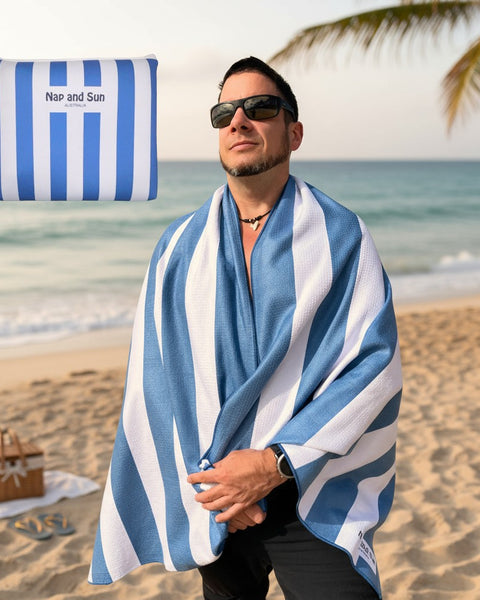 Man on a beach wearing a blue and white striped towel with a palm tree in the background.