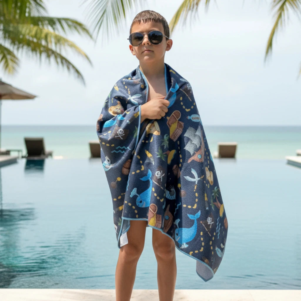 Child wrapped in a colorful pirate themed towel with a pool in the background