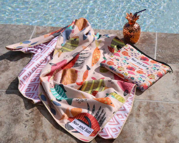 A colorful fish-print beach towel lies beside the pool.