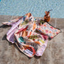 A colorful fish-print beach towel lies beside the pool.