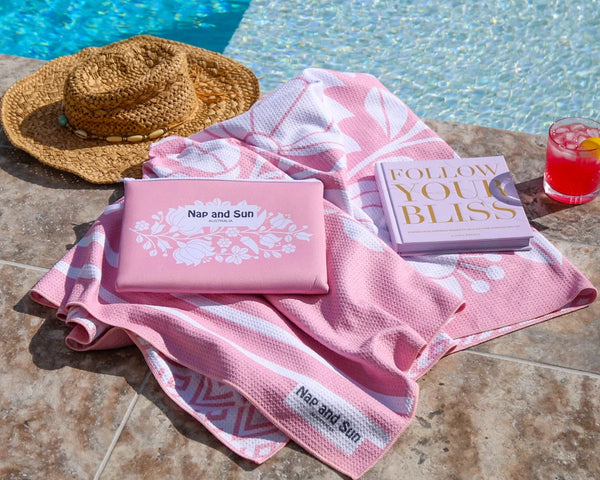 Pink sand-free waffle towel with a wetbag beside poolnext to pool