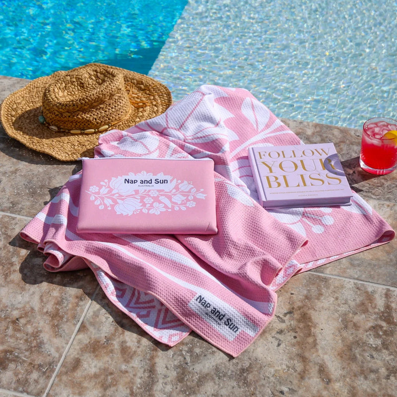 Pink sand-free waffle towel with a wetbag beside poolnext to pool
