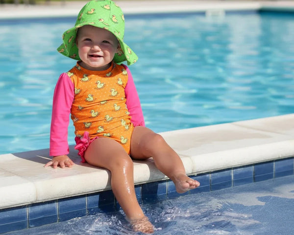 kid is sitting by to pool in colorful swimwear