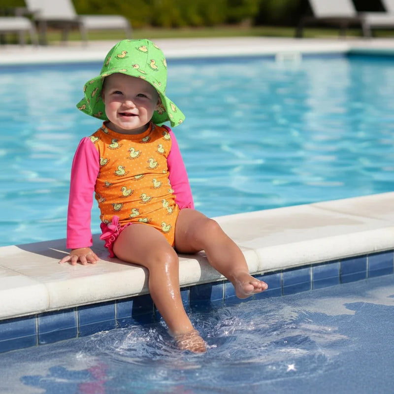 kid is sitting by to pool in colorful swimwear