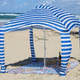 patterned picnic blanket with cabana on a sandy beach.