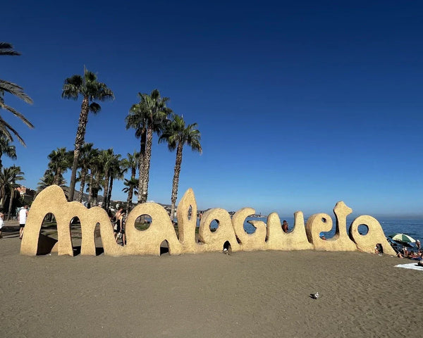 Malagueta sand monument on a sunny Malaga beach with the Mediterranean Sea and palm trees