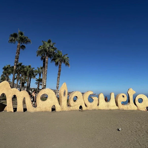 Malagueta sand monument on a sunny Malaga beach with the Mediterranean Sea and palm trees