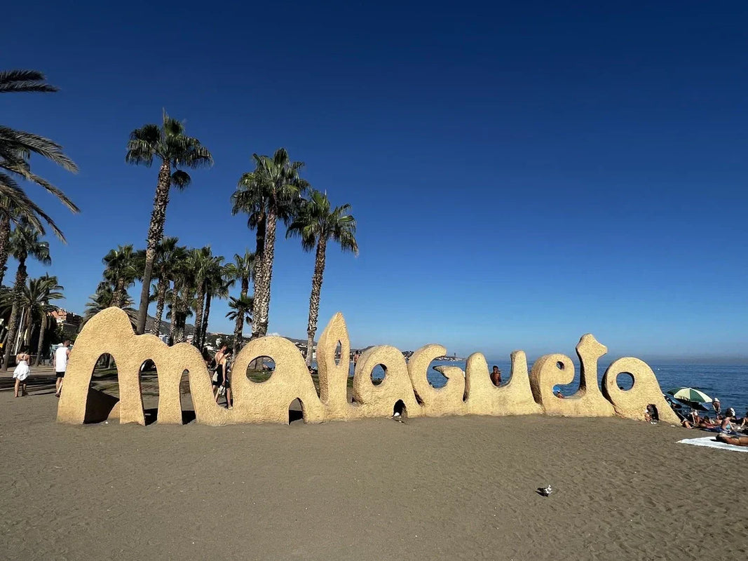 Malagueta sand monument on a sunny Malaga beach with the Mediterranean Sea and palm trees