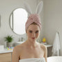 Woman with pink hair wrap and bunny ears in a bathroom