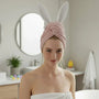 Woman with pink hair wrap and bunny ears in a bathroom