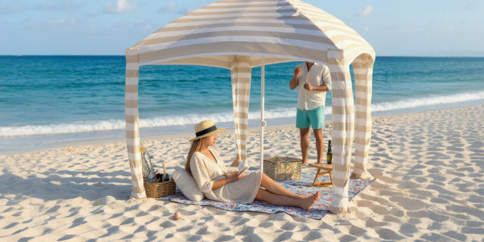 woman is reading on a beach mat under a cabana on the beach