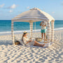 woman is reading on a beach mat under a cabana on the beach
