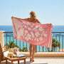 Woman with a Pink beach towel is standing in a terrace overlooking the ocean