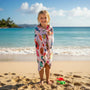 Little girl wrapped in a colourful beach towel on a beach