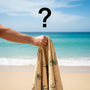 Hand holding a yellow beach towel on a beach with a question mark