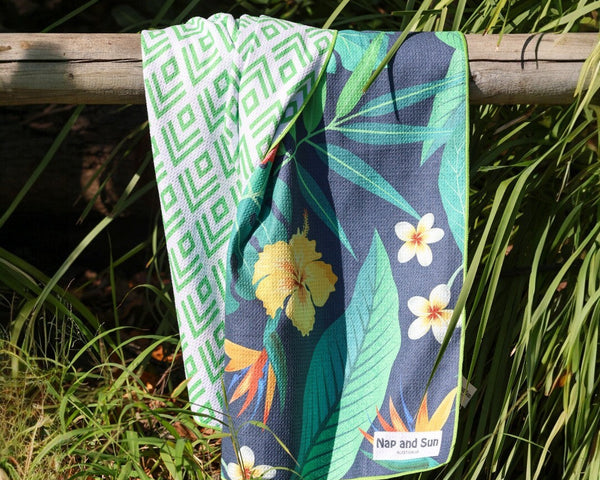 tropical pattern towel is hanging on a fence in a bush