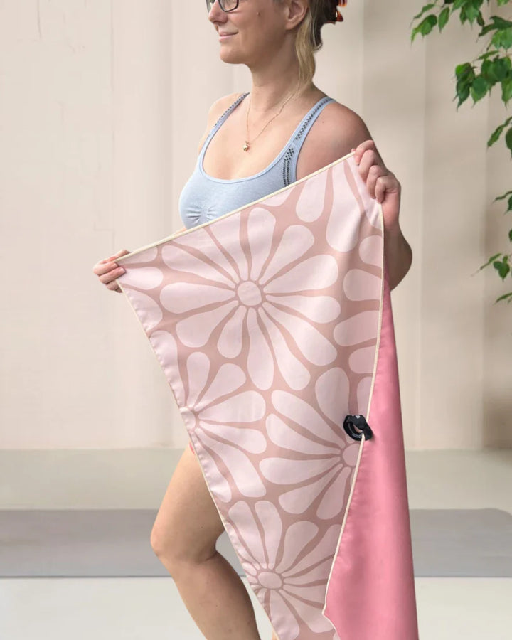 Back view of a woman in a sports top exercising in the gym, with a blue stars towel displayed on the left side of the image. Text overlay: 'Train like a champion: Sweat, Dry, Repeat.