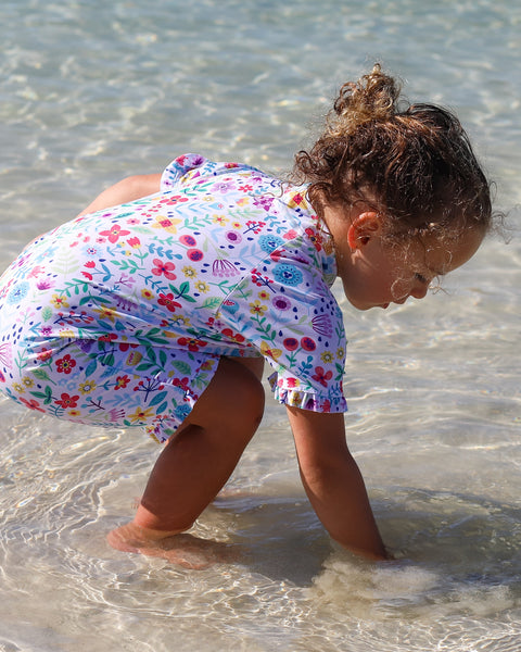 Child in a colorful swimsuit playing in clear water