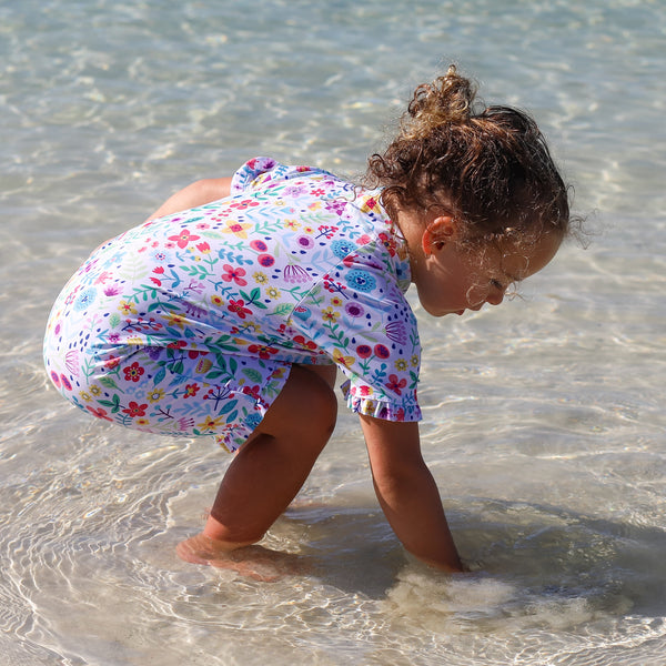 Child in a colorful swimsuit playing in clear water