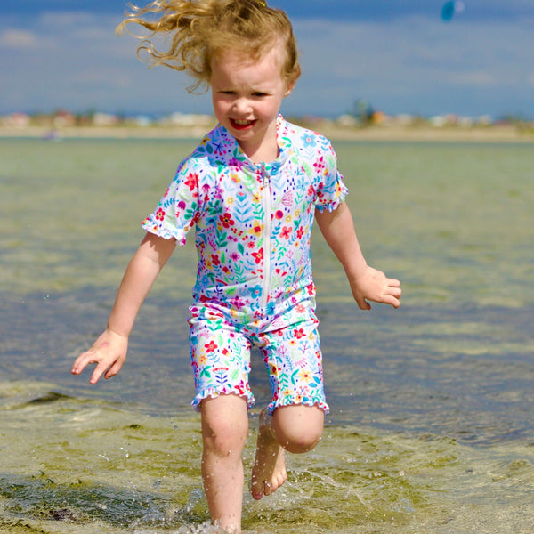 Child in a colorful swimsuit running on a beach