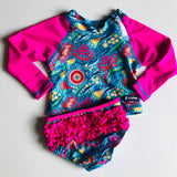 Colorful two piece children's swimsuit with pink long-sleeve rash guard and brief