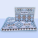 Nap and Sun Azure Tribe sand-free beach towel. double sided design front featuring a vibrant tribal pattern in shades of blue, white, and brown. Back: White background blue geometric lines. free matching wetbag included. 