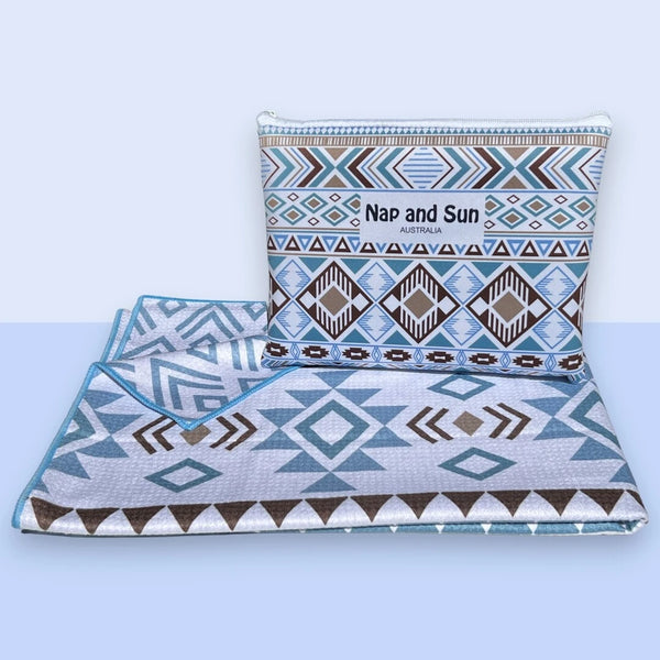 Nap and Sun Azure Tribe sand-free beach towel. double sided design front featuring a vibrant tribal pattern in shades of blue, white, and brown. Back: White background blue geometric lines. free matching wetbag included. 