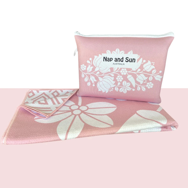 Nap and Sun Pink Bloom sand-free beach towel featuring a double sided design. Front: soft pink background with white floral pattern. Back: White background pink geometric lines. free matching wetbag included. 