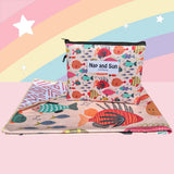 Nap and Sun Rainbow Reef sand-free beach towel for kids with a colorful underwater theme on the front, featuring vibrant coral, fish, and sea creatures on a light peachy background. Back: White background pink geometric lines. free matching wetbag included. 