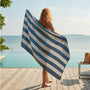 Woman stretching out a blue white striped beach towel next to a pool