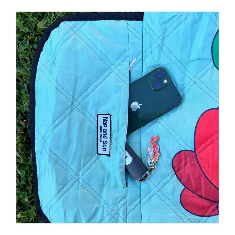 Close-up of a zip pocket on a picnic blanket with a phone and car key securely placed inside.