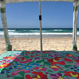 Nap and Sun Green-based picnic blanket with vivid flower pattern set up on the beach, with a sun cabana attached.