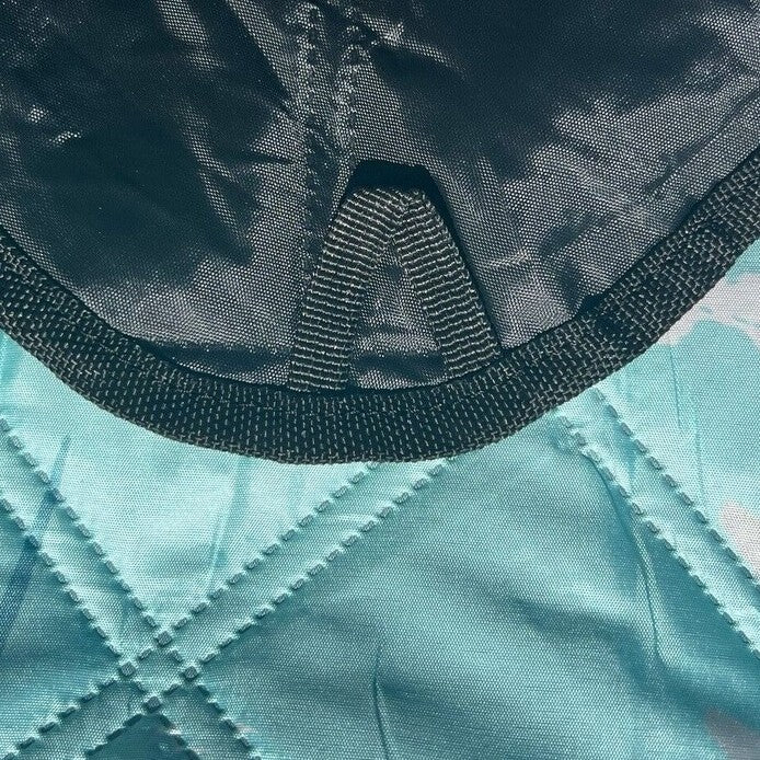 Close-up of the corner loop on the backside of a leafy-patterned picnic blanket.