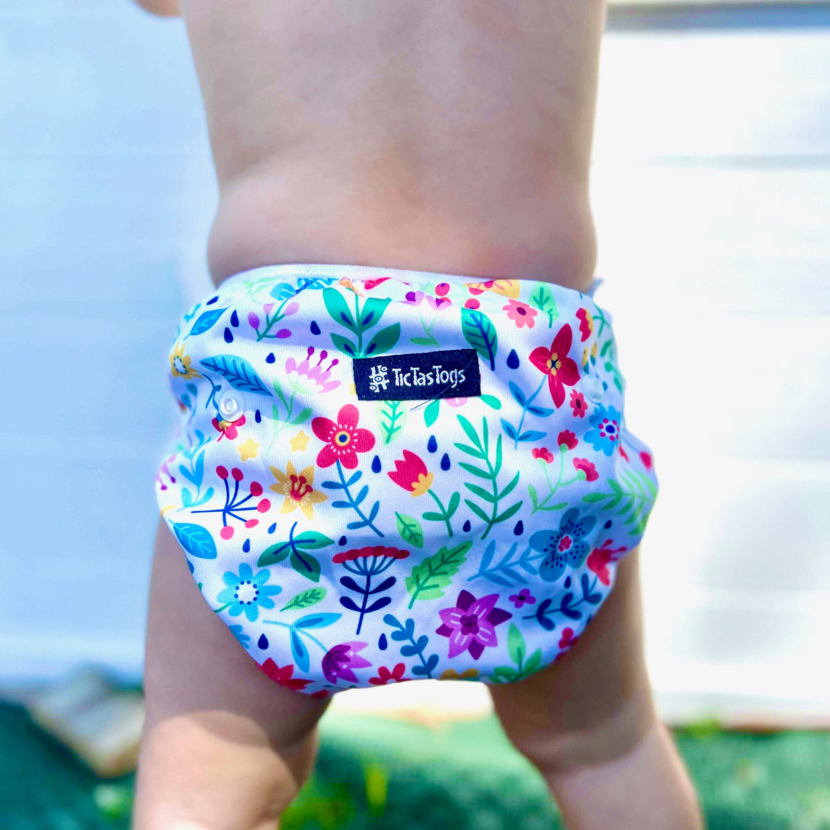 Colorful floral swim diaper worn by a child with a blurred background