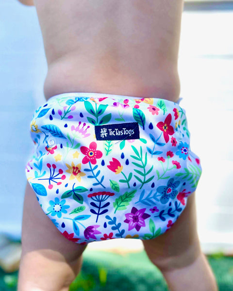 Colorful floral swim diaper worn by a child with a blurred background