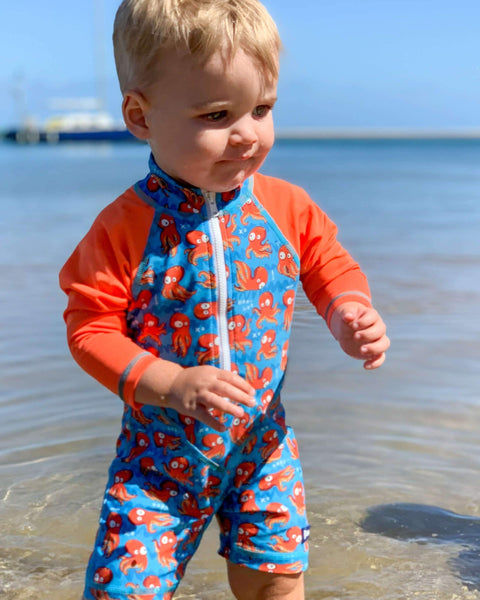 Child wearing a blue and red swimsuit with octopus pattern at the beach