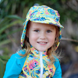 Child wearing a colorful raincoat and hat with a floral pattern, standing outdoors.