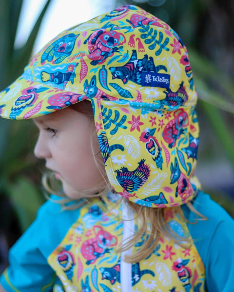 Child wearing a colorful patterned sun hat with a brand logo, standing outdoors.