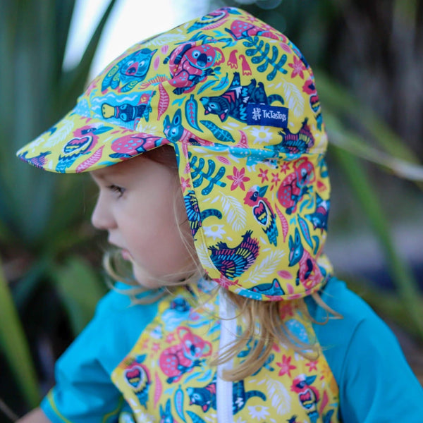 Child wearing a colorful patterned sun hat with a brand logo, standing outdoors.