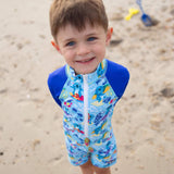 Child wearing a blue swimsuit with koala designs on a sandy beach