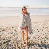 Woman standing on a sandy beach wearing a patterned cover-up.
