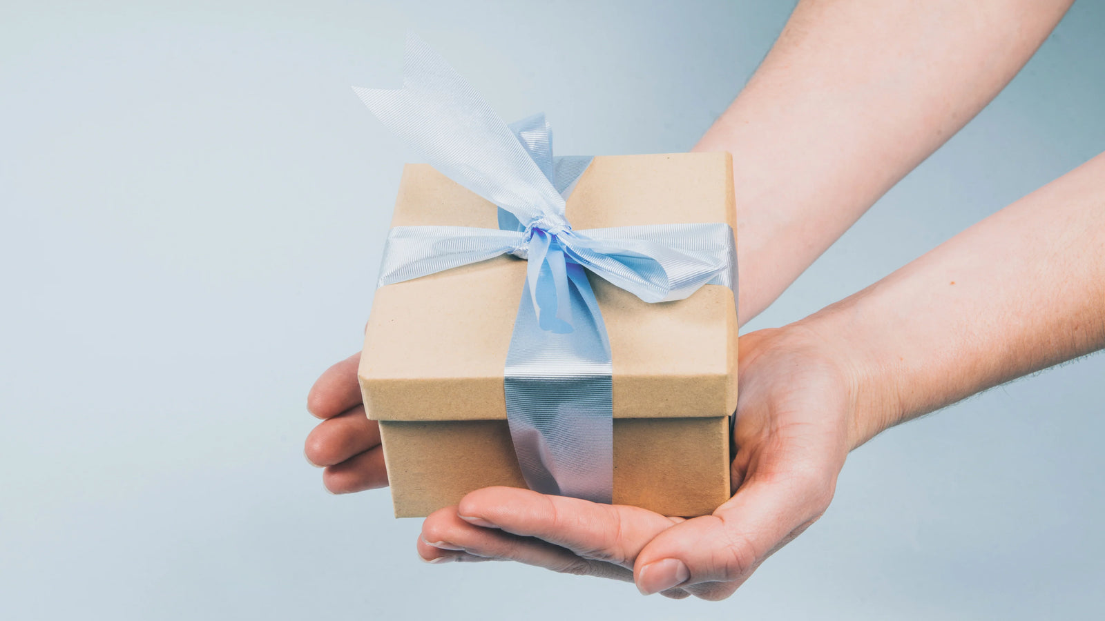 gift package in hand with a blue ribbon