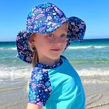 Child wearing a floral sun hat and matching scarf on a beach