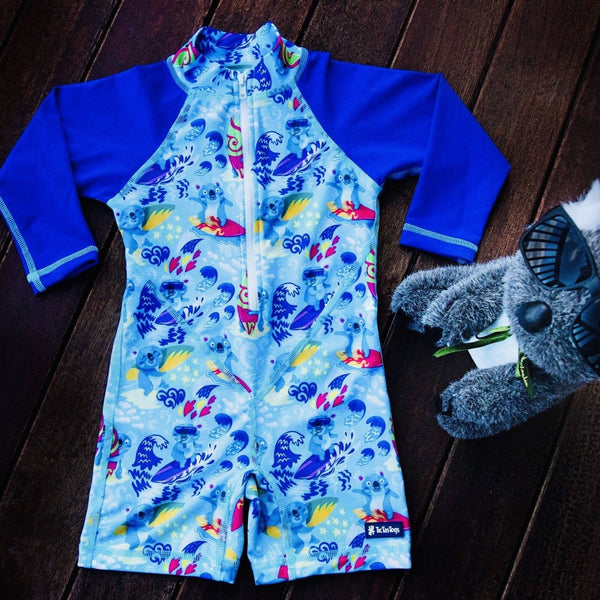 Children's one piece blue swimsuit with koala pattern on a wooden surface