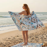 Woman on a beach holding an azureblue patterned towel 