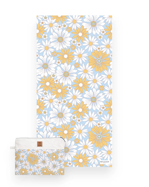 White and yellow daisy flower patterned beach towel on a light blue bachkground with a matching bag.
